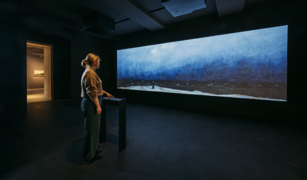 Eine Frau blickt auf eine Installation, die eine Landschaft zeigt.