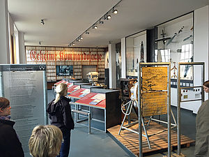 Besucherinnen und Besucher schauen sich in der Ausstellung Schautafeln und Exponate an. 