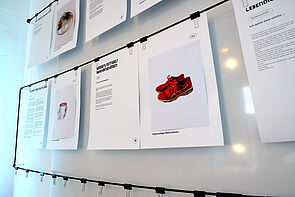 Fotos an der Wand. Auf einem sind rote Schuhe zu sehen.