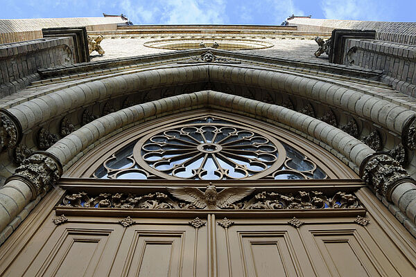 Das sandfarbene Eingangsportal der Neustrelitzer Schlosskirche. Das Foto wurde von unten nach oben aufgenommen und legt den Fokus auf die Verzierungen. 