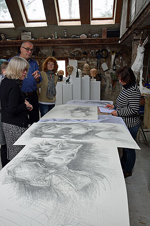 Die Kunstkommission betrachtet Zeichnungen des Künstlers.