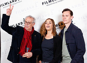 Drei Filmschaffende stehen vor einer Interviewwand zum Filmkunstfest.