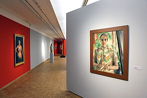 Bilder mit Porträts hängen in der Ausstellung.