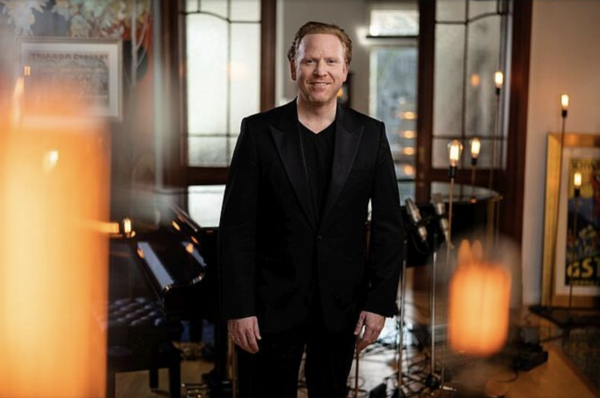 Porträt eines Musikers vor einer Bühne.