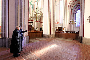 Zwei Männer in der Kirche, sie schauen zum Fenster.