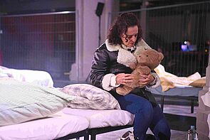 Eine Schauspielerin hält einen Teddybären in den Händen.