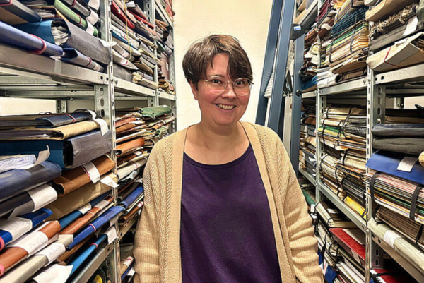 Eine Frau steht zwischen Regalen.