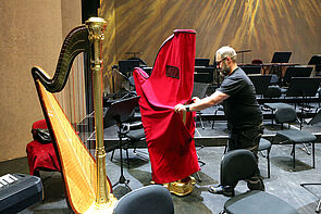 Ein Mann entfernt den Schutzmantel einer Harfe.