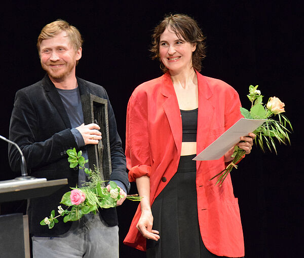 Ein Mann und eine Frau auf der Bühne. Sie werden für ihren Film ausgezeichnet.