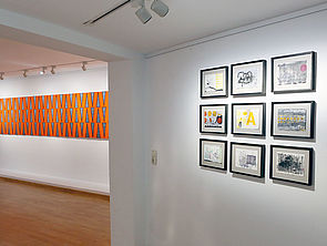 Rechts an der Wand: neun Bilder. Links: eine längliche Installation.