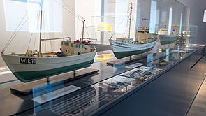Drei Segelbootmodelle in einer Glasvitrine.