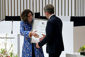 Eine Frau überreicht eine Urkunde.