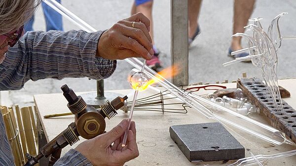 Ein Mann bearbeitet Glas an einer Gasflamme.
