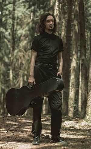 Ein Mann mit einer Gitarre im Wald