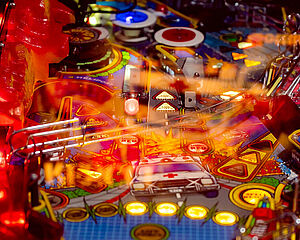 Detailansicht eines Flipperautomaten. Die Spielfläche leuchtet bunt. 