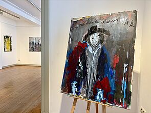 Ein Gemälde auf einer Staffelei. Das Bild ist ein Porträt.