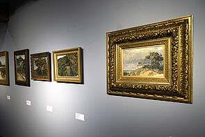 Gerahmte Bilder hängen nebeneinander an der Wand.