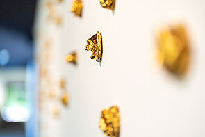 Mehrere goldene Reliefs hängen an der Wand.