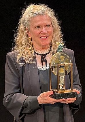 Eine Frau. Sie hält eine Trophäe in der Hand. Die Trophäe ist der Goldene Ochse.