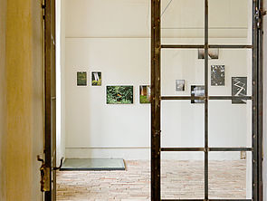 Eine Glastür mit Holzstreben. Dahinter hängen Bilder an einer Wand.