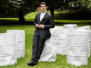 Ein junger Musiker lehnt an einem weißen Fass.