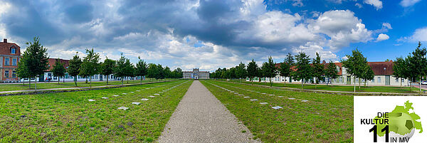 Ein Schotterweg. Links und rechts davon ist Wiese. Daneben stehen Bäume und Fachwerkhäuser. Am Ende des Weges befindet sich ein Schloss. In der Ecke steht das Logo zur Serie. Es besteht aus den Umrissen von MV, einem Fußball und dem Schriftzug "Die Kultur 11 in MV".