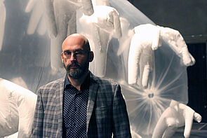 Ein Künstler steht vor einem seiner Installationen.