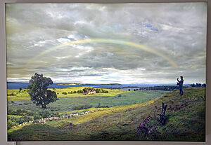 Ein Gemälde mit Wiesen, Hecken, einem Baum und einem Regenbogen am Horizont.