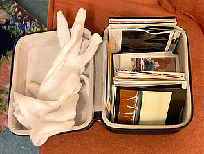 Ein kleines Case mit Fotografien und einem weißen paar Handschuhen.