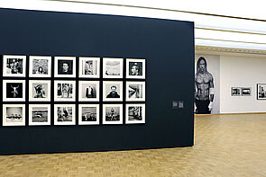 Kleine Porträts hängen an der Wand. Im Hintergrund ist Iggy Pop groß zu sehen.