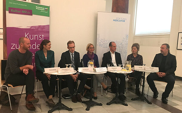 Sieben Frauen und Männer, darunter Kultusministerin Birgit Hesse, sitzen nebeneinander an vier runden Tischen.
