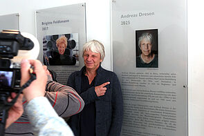 Ein Mann steht vor einer Tafel und wird fotografiert.