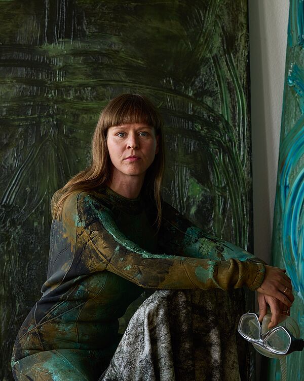 Porträt einer Künstlerin. Sie sitzt auf einem Stuhl.