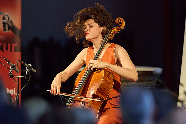 Eine Frau sitzt auf einem Stuhl und spielt Cello.