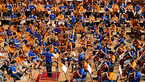 Ein Saal voller junger Musikerinnen und Musiker, die ihre Instrumente spielen.