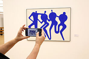 Blick durch eine Handykamera auf ein Gemälde.