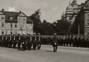 Historisches Foto zeigt Menschen in Uniform beim Marschieren.