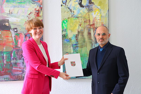 Eine Frau überreicht einem Mann eine Urkunde.