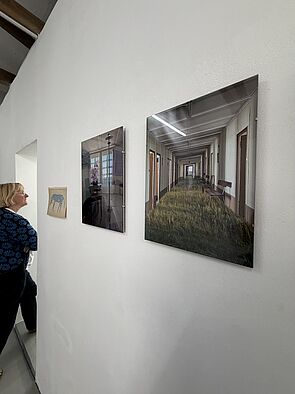 Eine Frau geht durch eine Tür. An der Wand hängen Fotos.