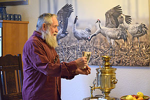 Wolf Spillner steht vor einem großen Wandfoto mit Vögeln.