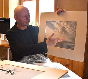 Andre van Uehm hält eine Fotografie in der Hand.