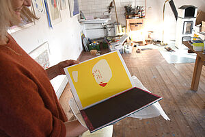 Tanja Zimmermann hält ein aufgeschlagenes Buch in der Hand. Es ist ein Kunstwerk.