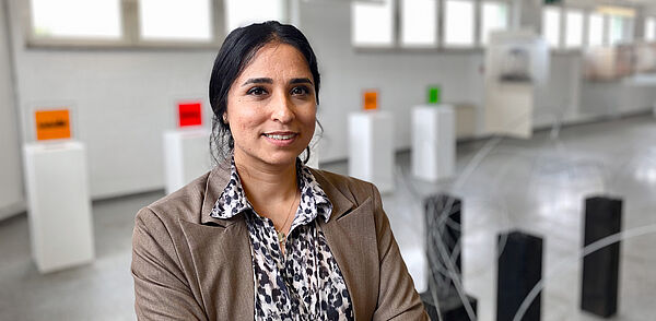Kuratorin Zahra Hasson-Taheri steht vor Kunstobjekten der Ausstellung. 