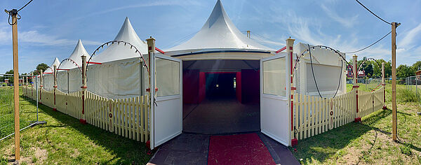Ein großes, weißes Zelt. Die Tür ist offen. 