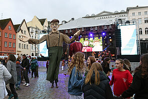 Riesige Figuren tanzen auf dem Marktplatz.