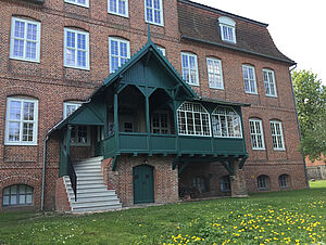 An der Hinterfassade befindet sich eine grüne Veranda mit Treppe zum Garten.