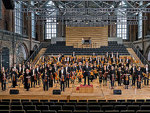 Viele Musiker. Sie stehen mit ihren Instrumenten auf einer Bühne.