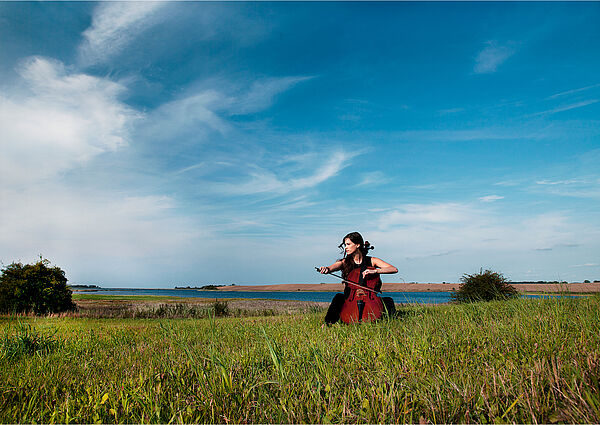 Eine Frau spielt auf ihrem Instrument in der Natur.
