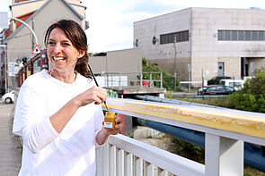 Die Künstlerin lächelt vor dem Geländer.