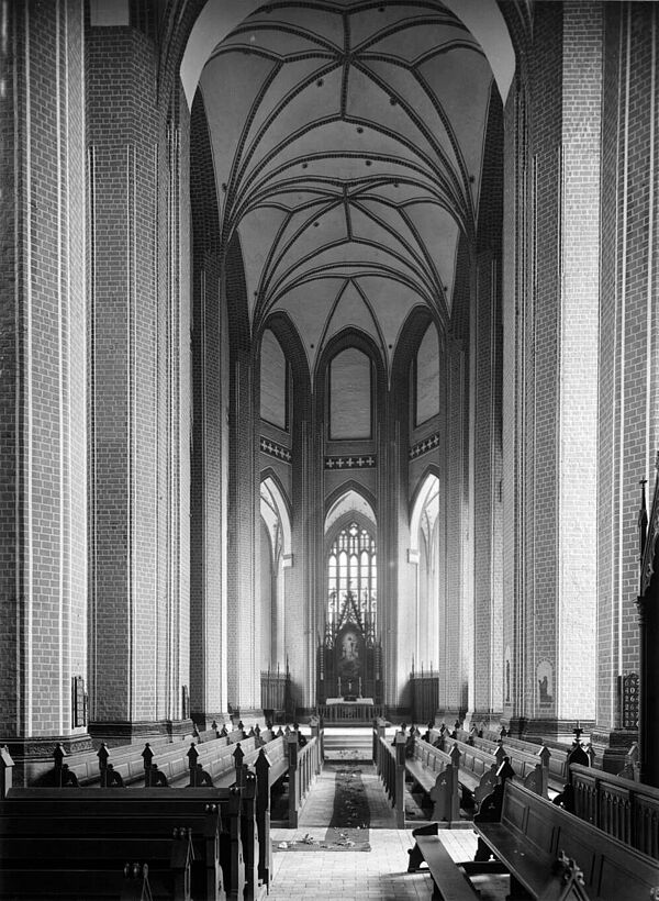 Eine Schwarz-Weiß-Aufnahme der Klosterkirche von innen. Mit vielen Kirchenbänken.